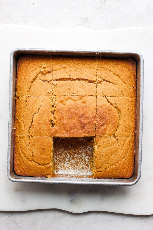 Gluten Free Cornbread fully cut in the baking pan and one piece removed.