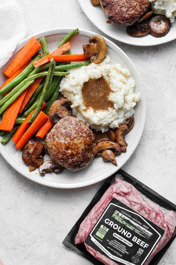 Healthy Homemade Salisbury Steak on a plate with mashed potatoes and gravy and roasted veggies.