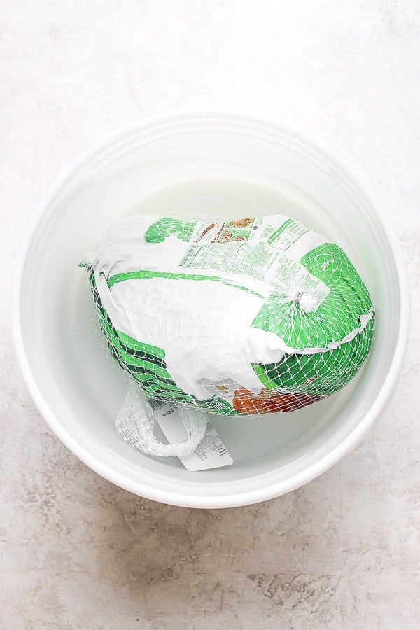 A packaged turkey breast sitting in a water bath. 