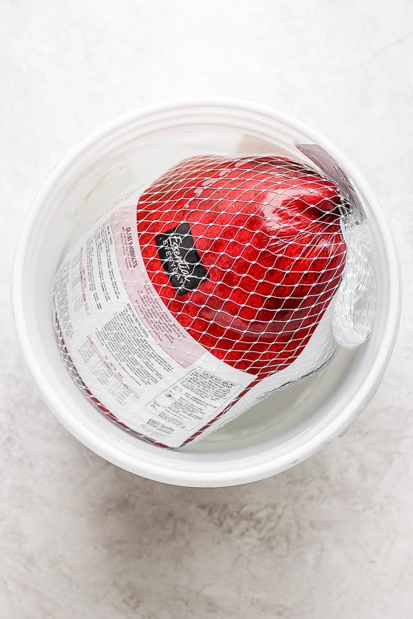 A packaged turkey sitting in a cold water bath. 