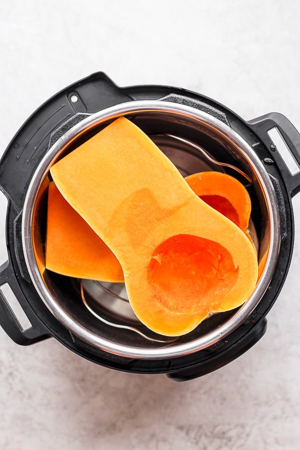Two butternut squash halves placed in the Instant Pot.
