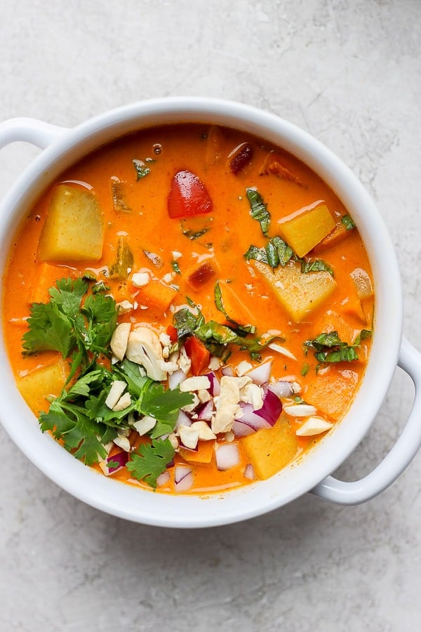Sweet potato curry in a white bowl with toppings.