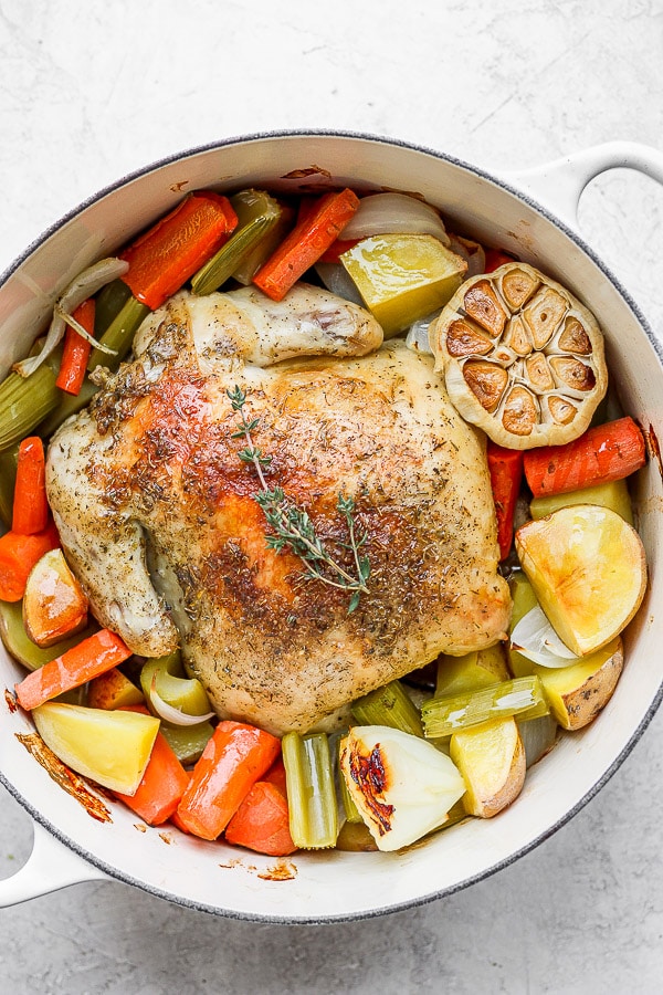 Whole roasted chicken in Dutch oven with veggies and potatoes. 
