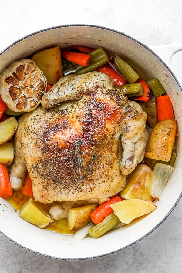 Whole roasted chicken in Dutch oven with veggies and potatoes. 
