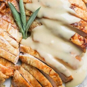 Smoked Turkey Breast on a plate, sliced, with gravy on top.