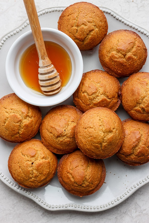 Gluten free cornbread muffins with a dish of honey.