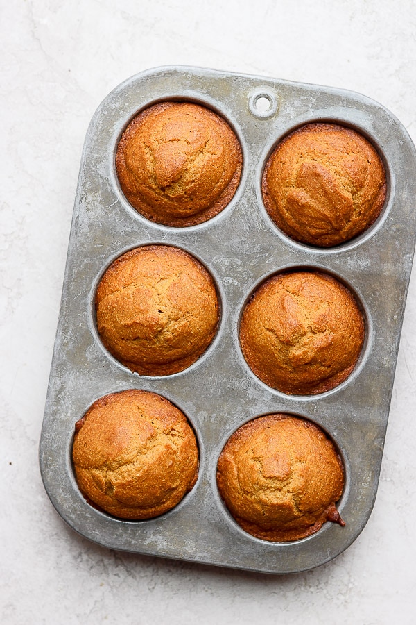 Baked cornbread muffins in a silver muffin tin.