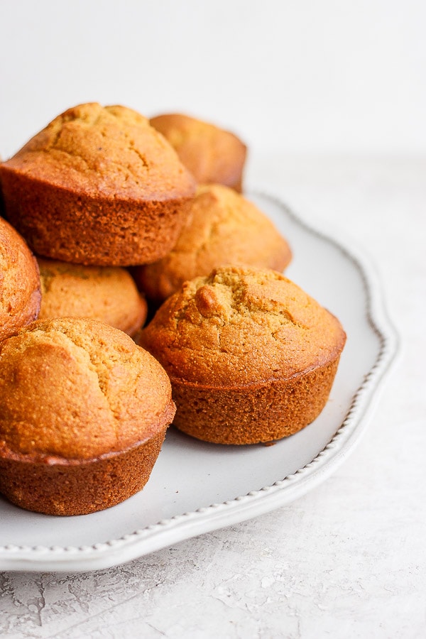 A pile of cornbread muffins on a white plate.