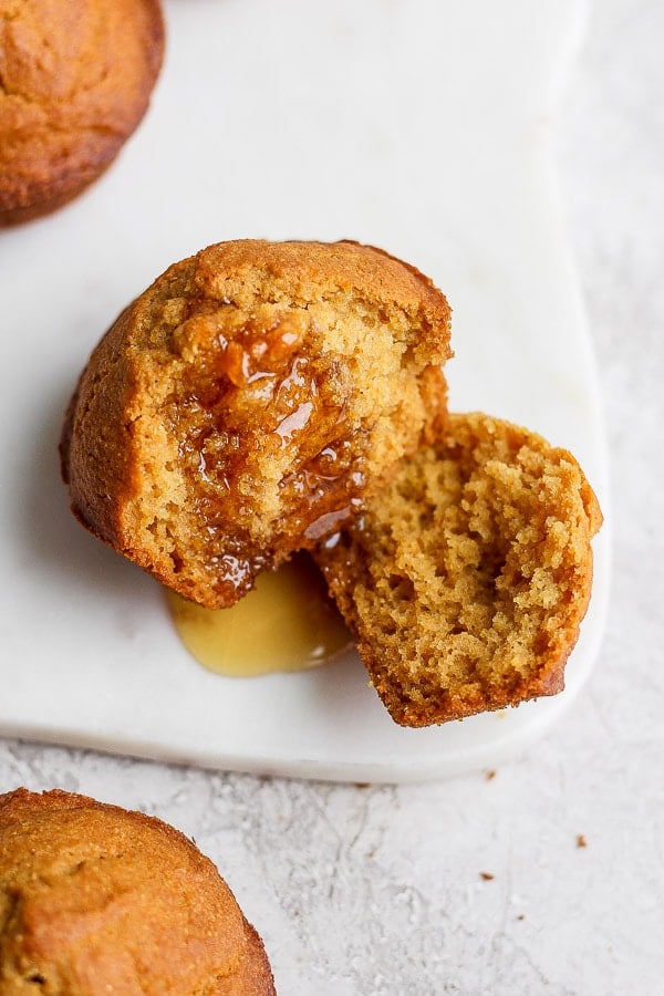 A cornbread muffin cut in half with a bit of honey on top.