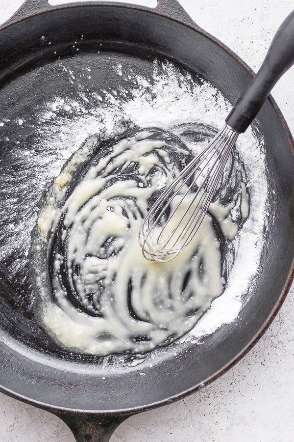 Cast iron skillet with a whisk combining melted ghee and tapioca starch. 