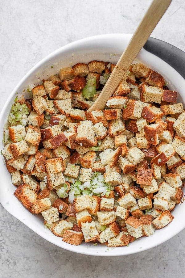 Bowl of dried gluten free bread cubes with onion and celery. 