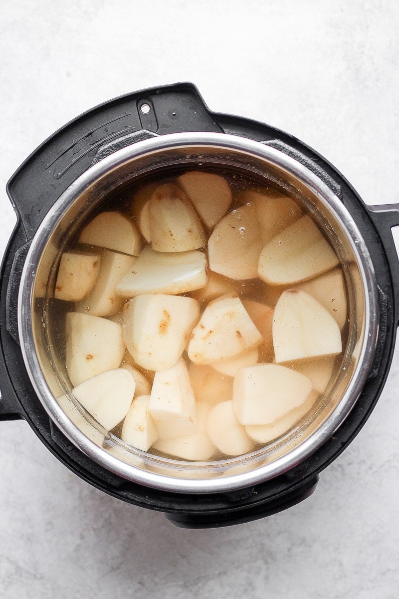 Instant pot with chunks of peeled russet potatoes and water to cover them.