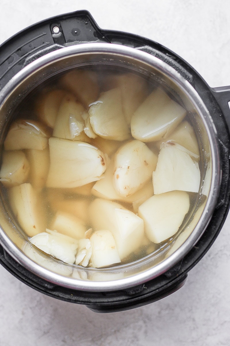 Instant Pot with cooked chunks of russet potatoes in water.