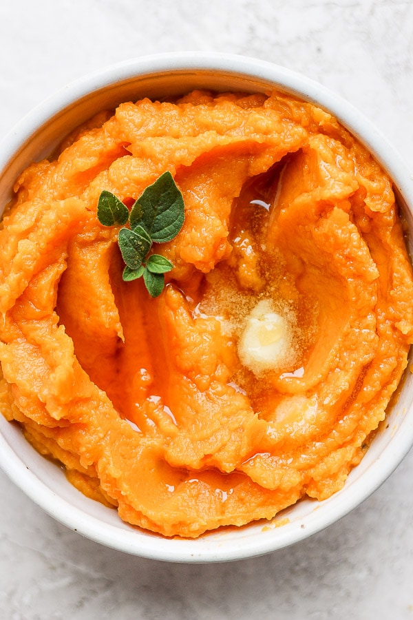 Bowl of mashed sweet potatoes with melted ghee on top.
