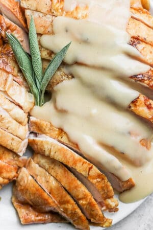 Smoked Turkey Breast on a plate, sliced, with gravy on top.