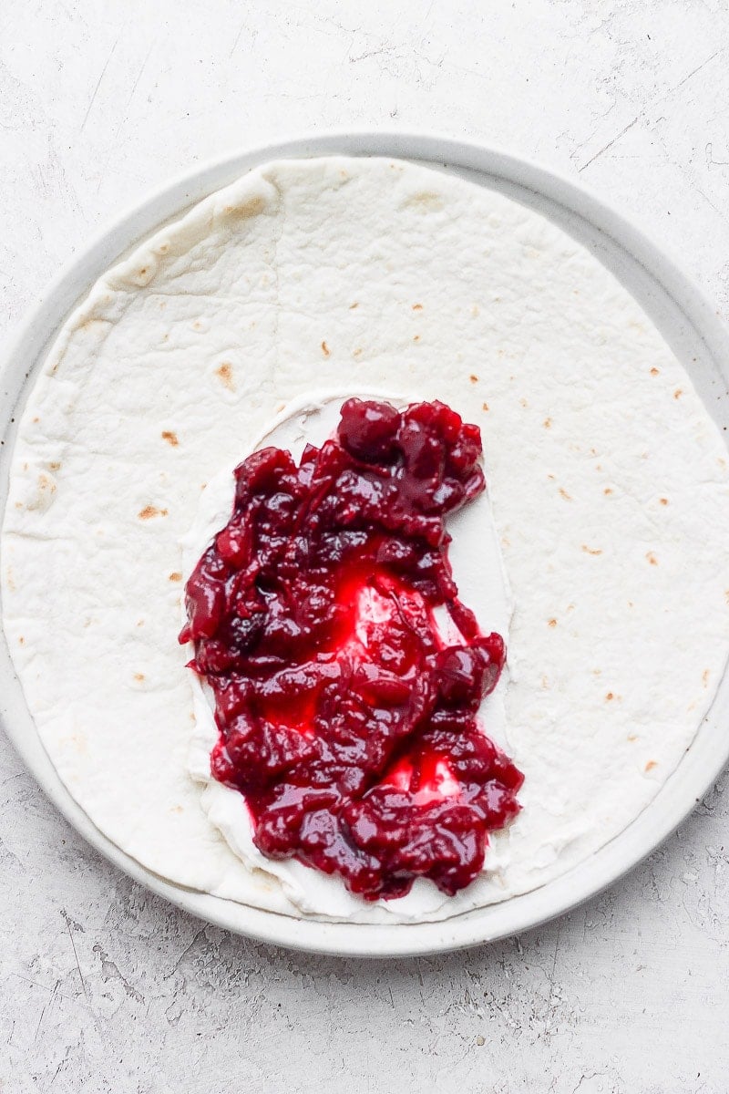 A tortilla with dairy-free cream cheese and cranberry sauce.