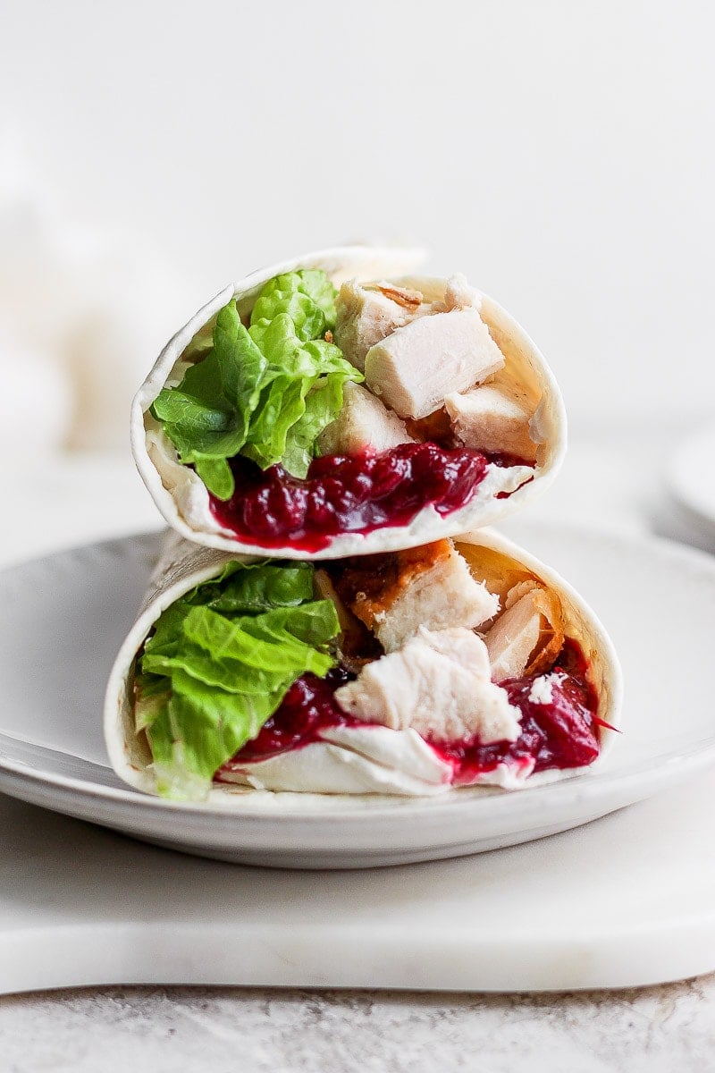 2 turkey cranberry wraps stacked on a white plate.