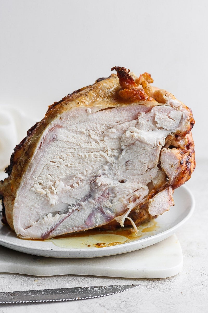 A carved turkey breast on a white plate.