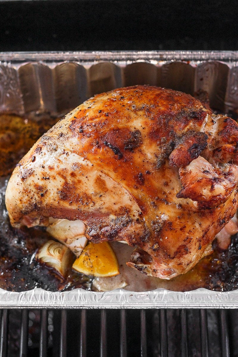 A cooked turkey breast in an aluminum tray on the grill.
