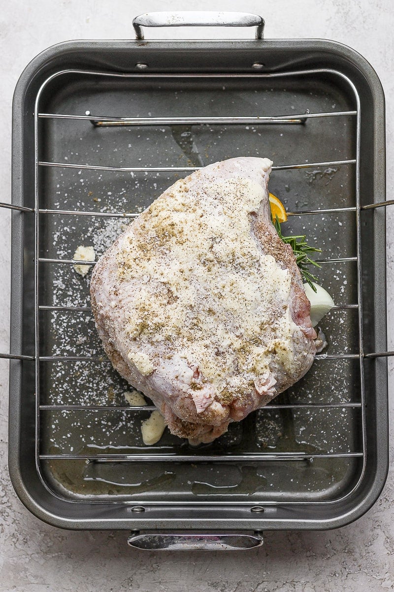 A prepared and stuffing turkey breast sitting in a roasting pan, uncooked. 