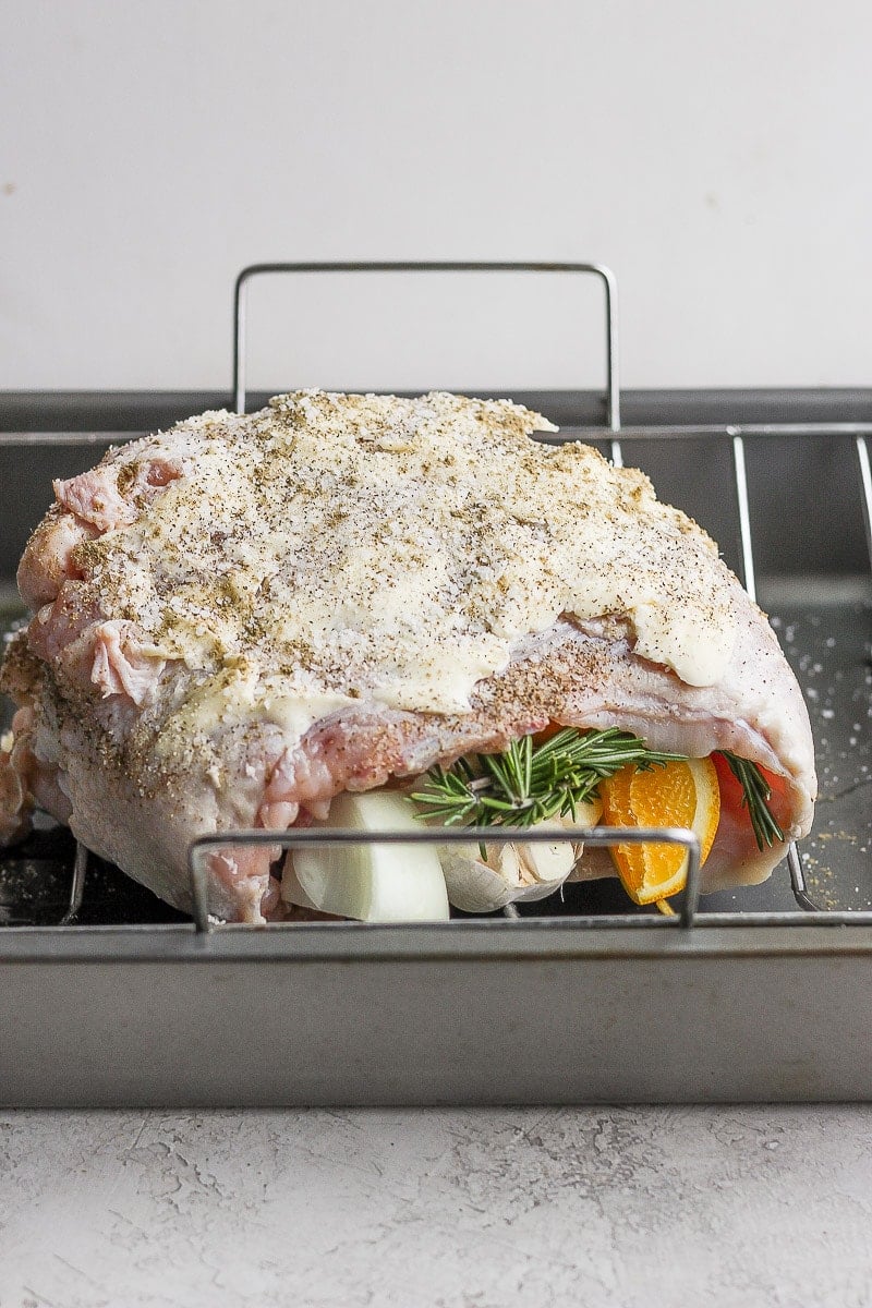 A prepared and stuffing turkey breast sitting in a roasting pan, uncooked. 