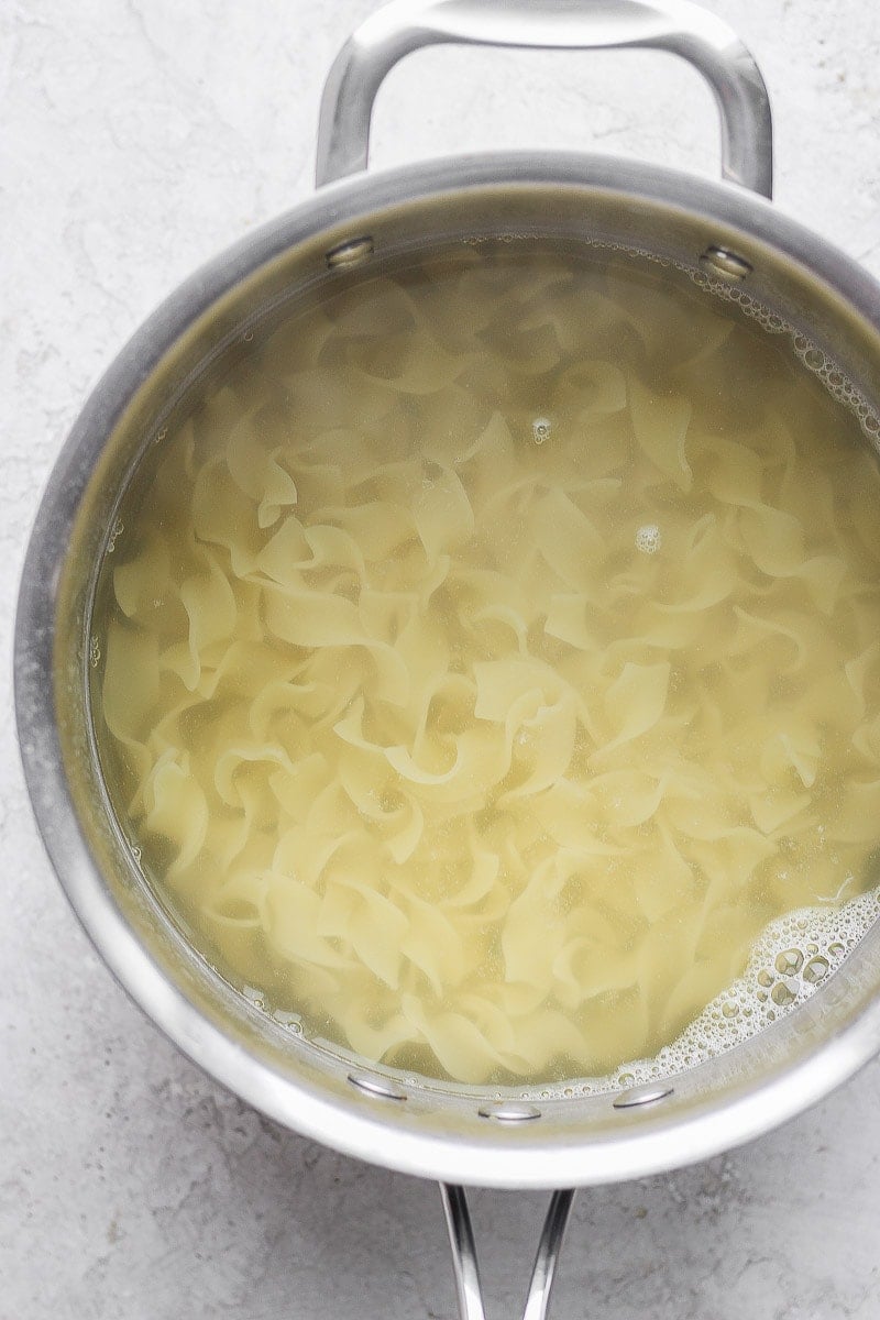 A medium pot with cooked noodles and water.
