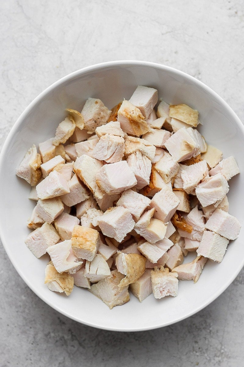 A white bowl with cut-up cooked turkey.