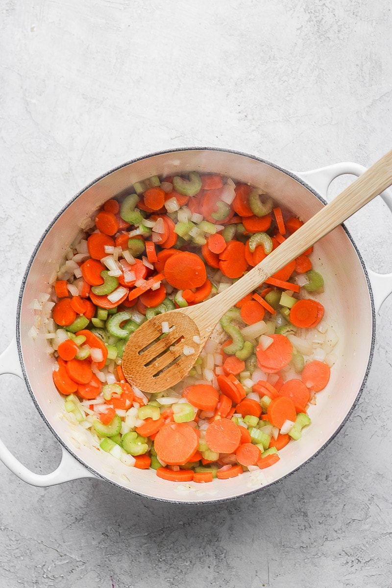 A large pot with cooked carrots, celery, and onions.
