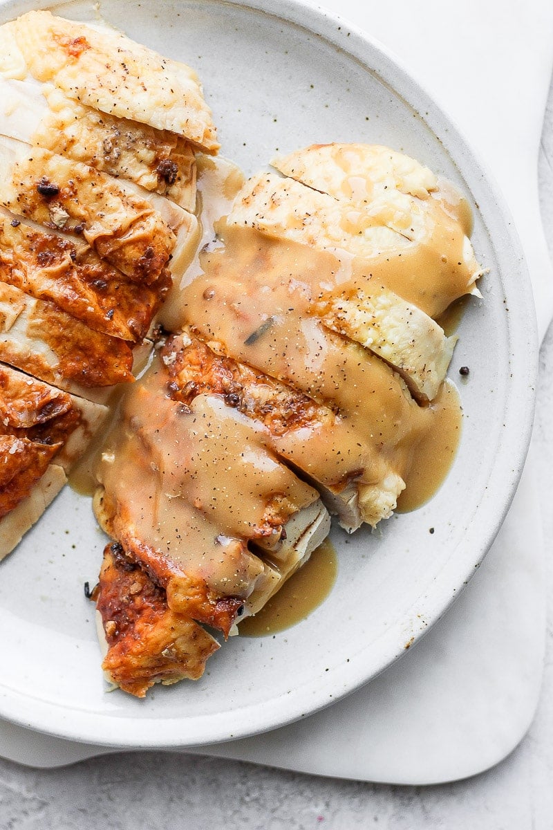 Plate with sliced chicken breast covered in chicken gravy. 