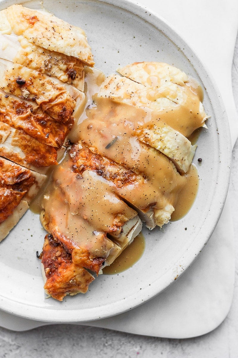 Chicken gravy on sliced chicken breasts on a plate.