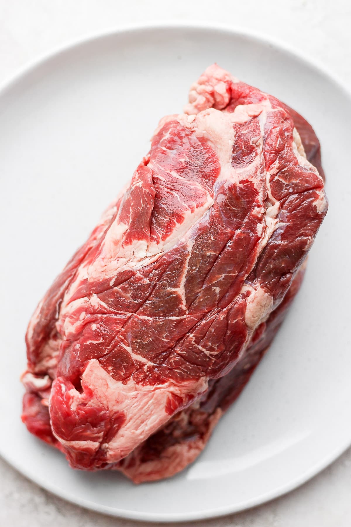 A beef roast on a plate, uncooked.