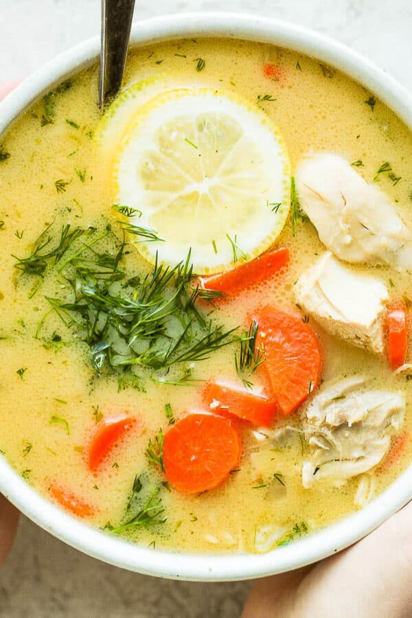Two hands holding a bowl of Greek Lemon Chicken Soup.