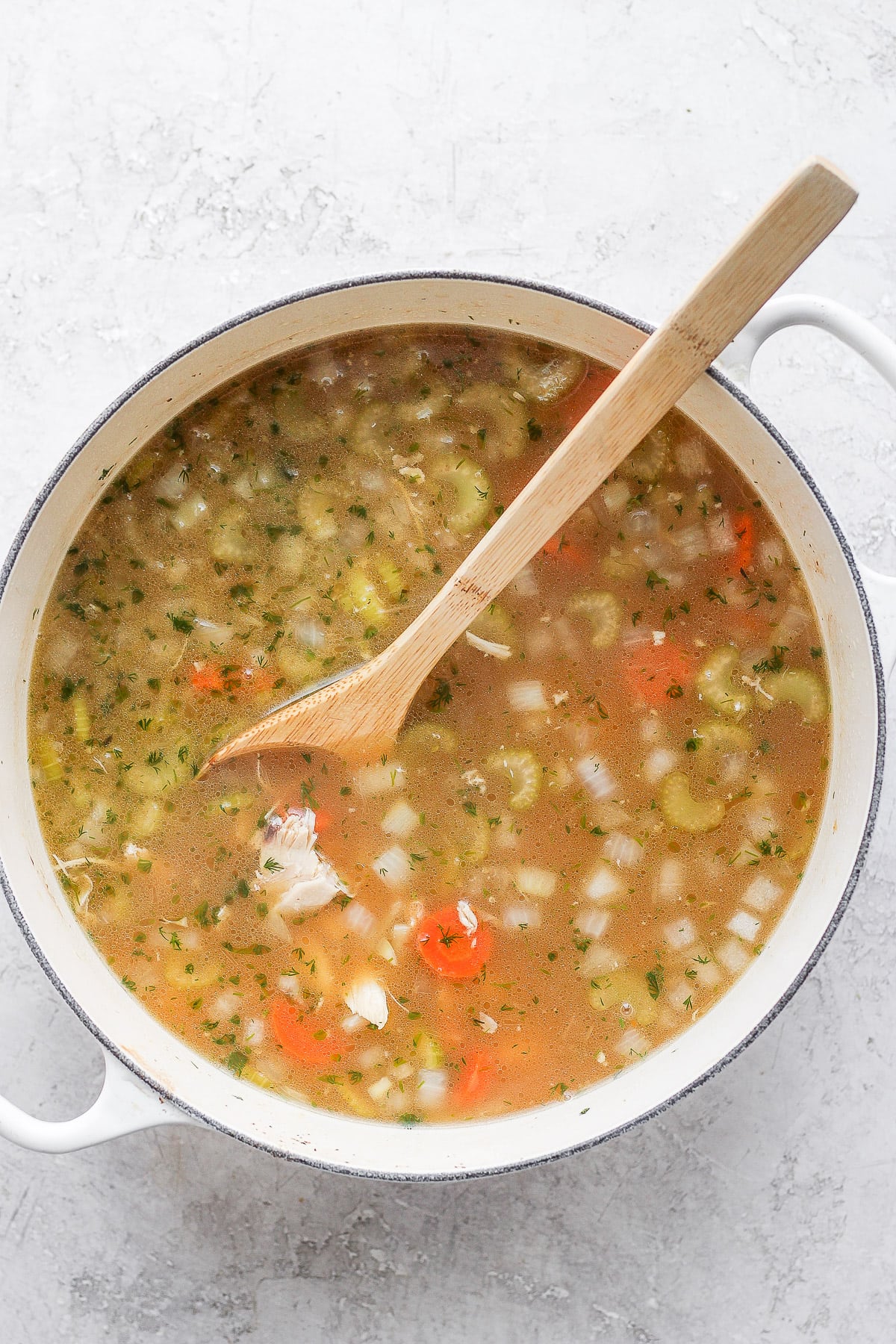 Dutch oven filled with broth and veggies. 