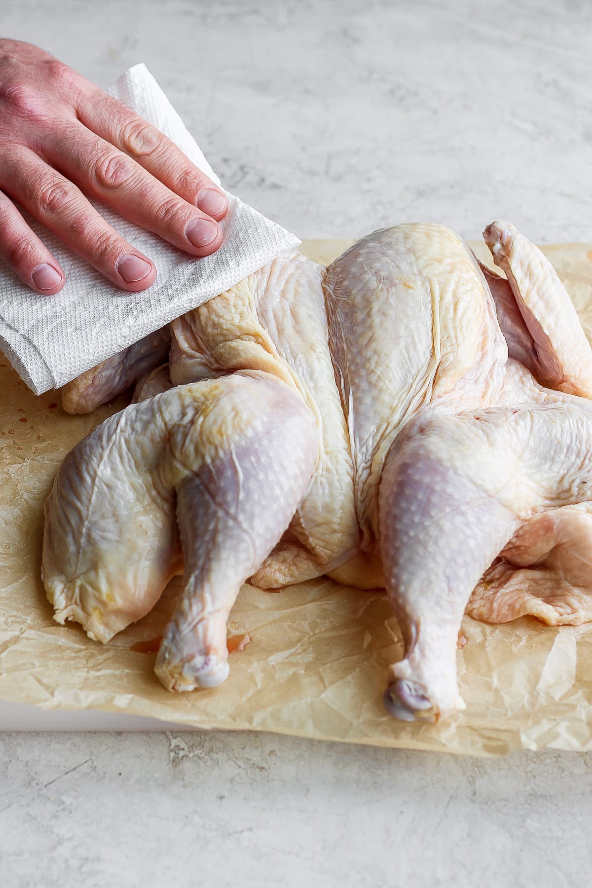 Patting dry a spatchcocked chicken. 