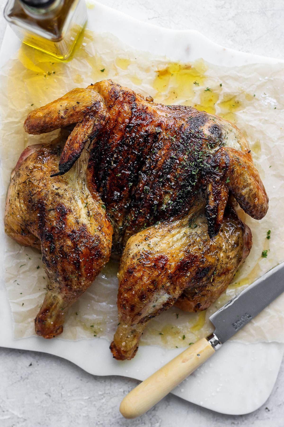 Spatchcock chicken on a piece of parchment paper with olive oil and salt.