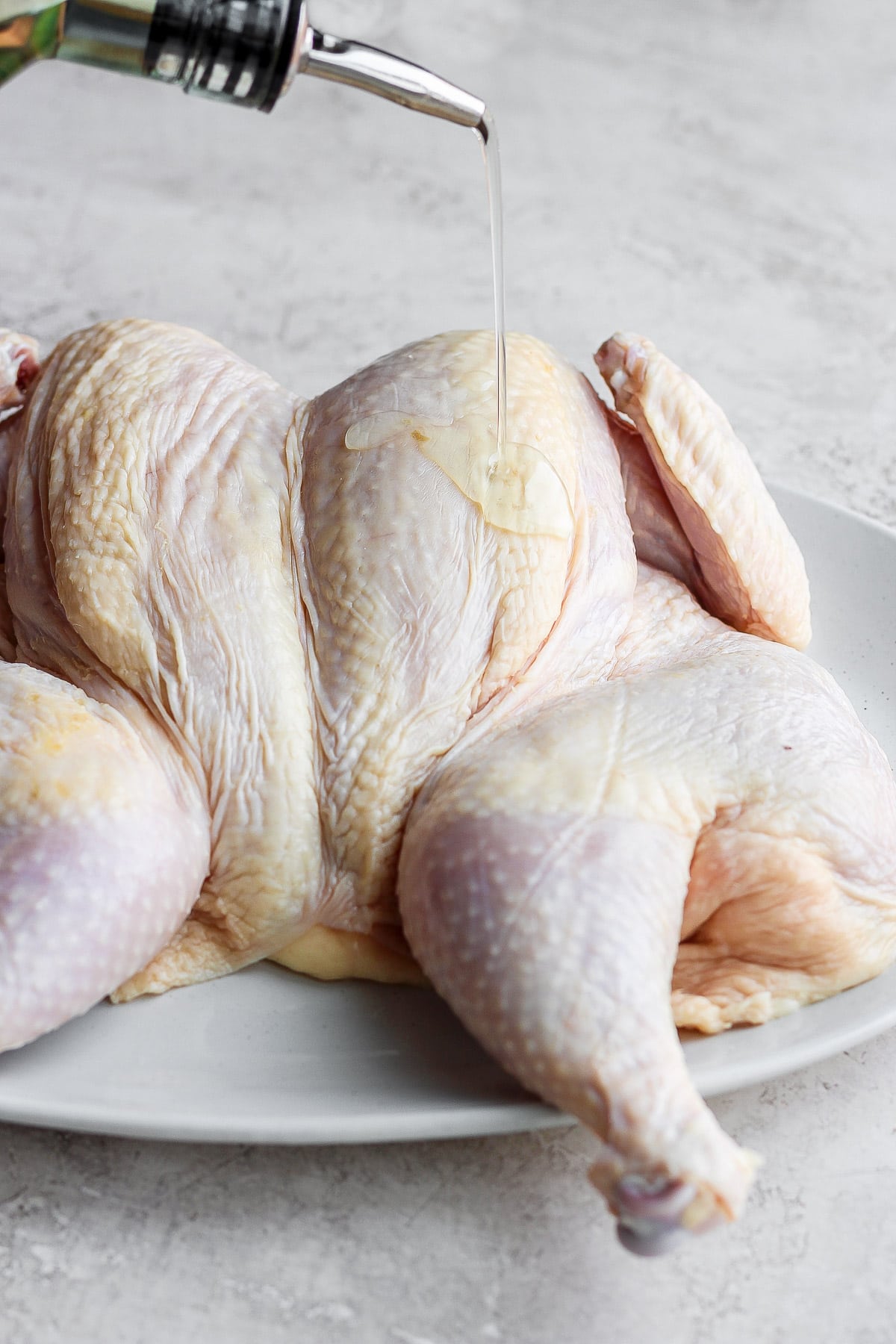 Pouring oil onto a spatchcocked chicken. 