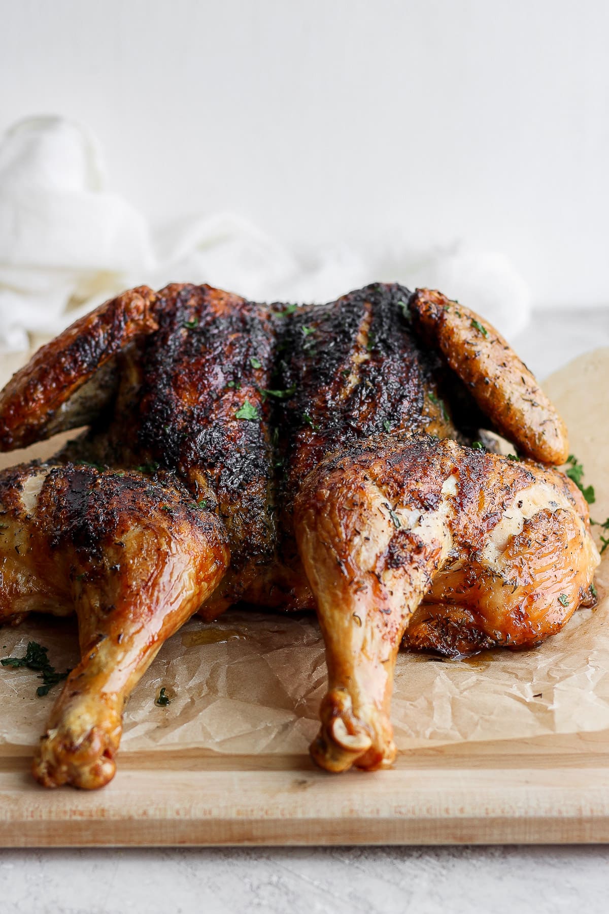 A whole, spatchcock chicken on a cutting board and parchment paper. 