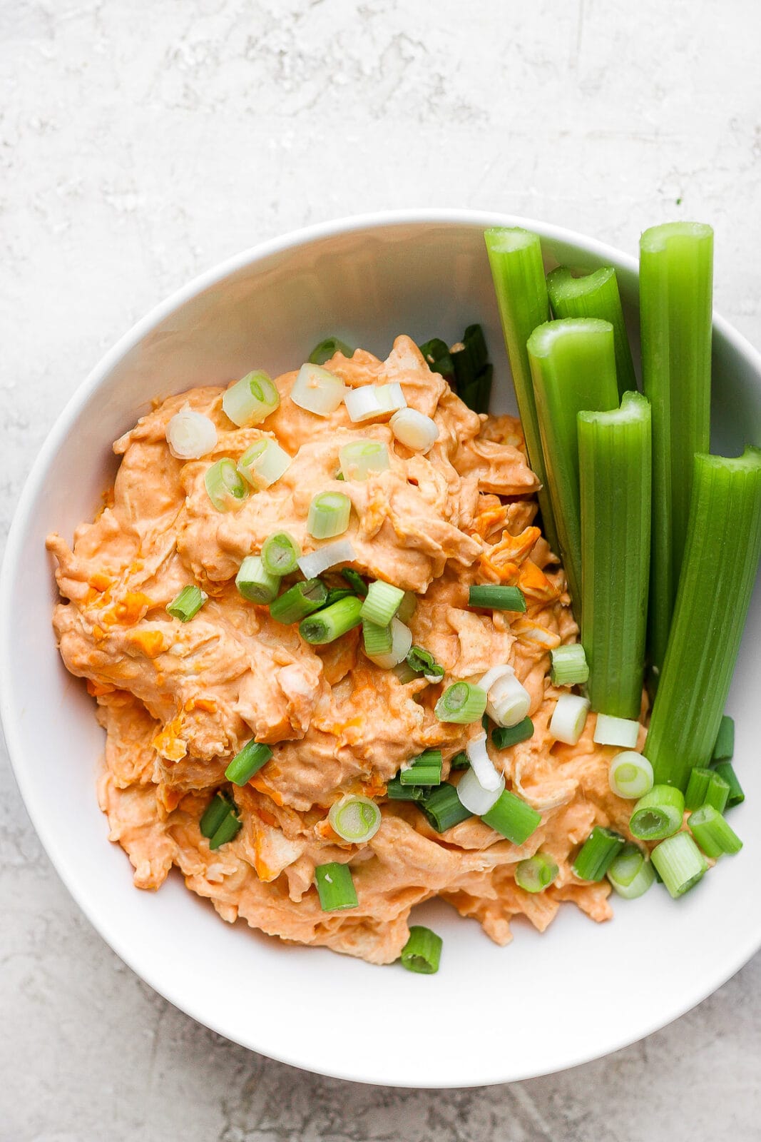 Bowl of healthy buffalo chicken dip with celery and green onions. 