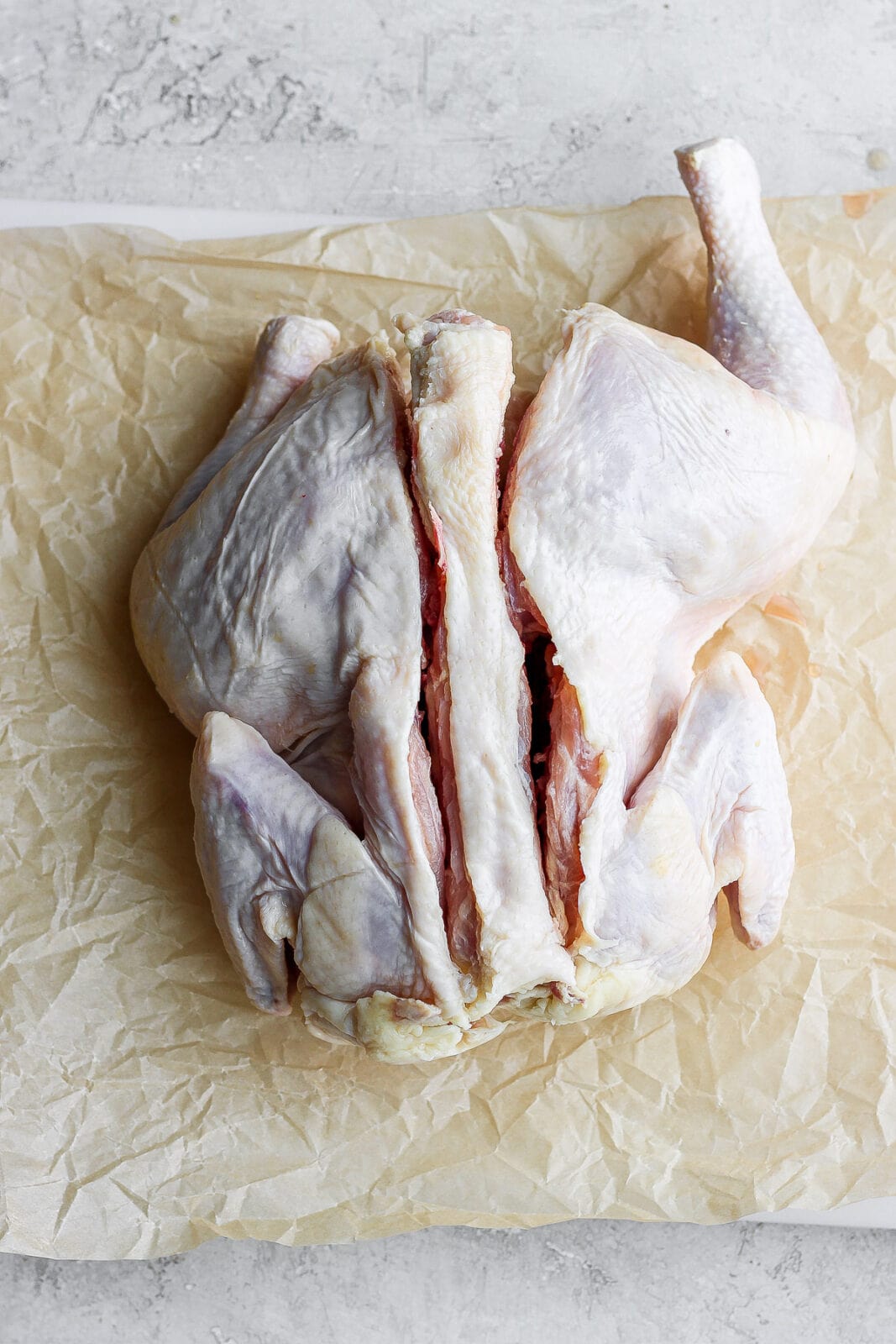 The backbone of the chicken cut along both sides, but still sitting in the chicken. 