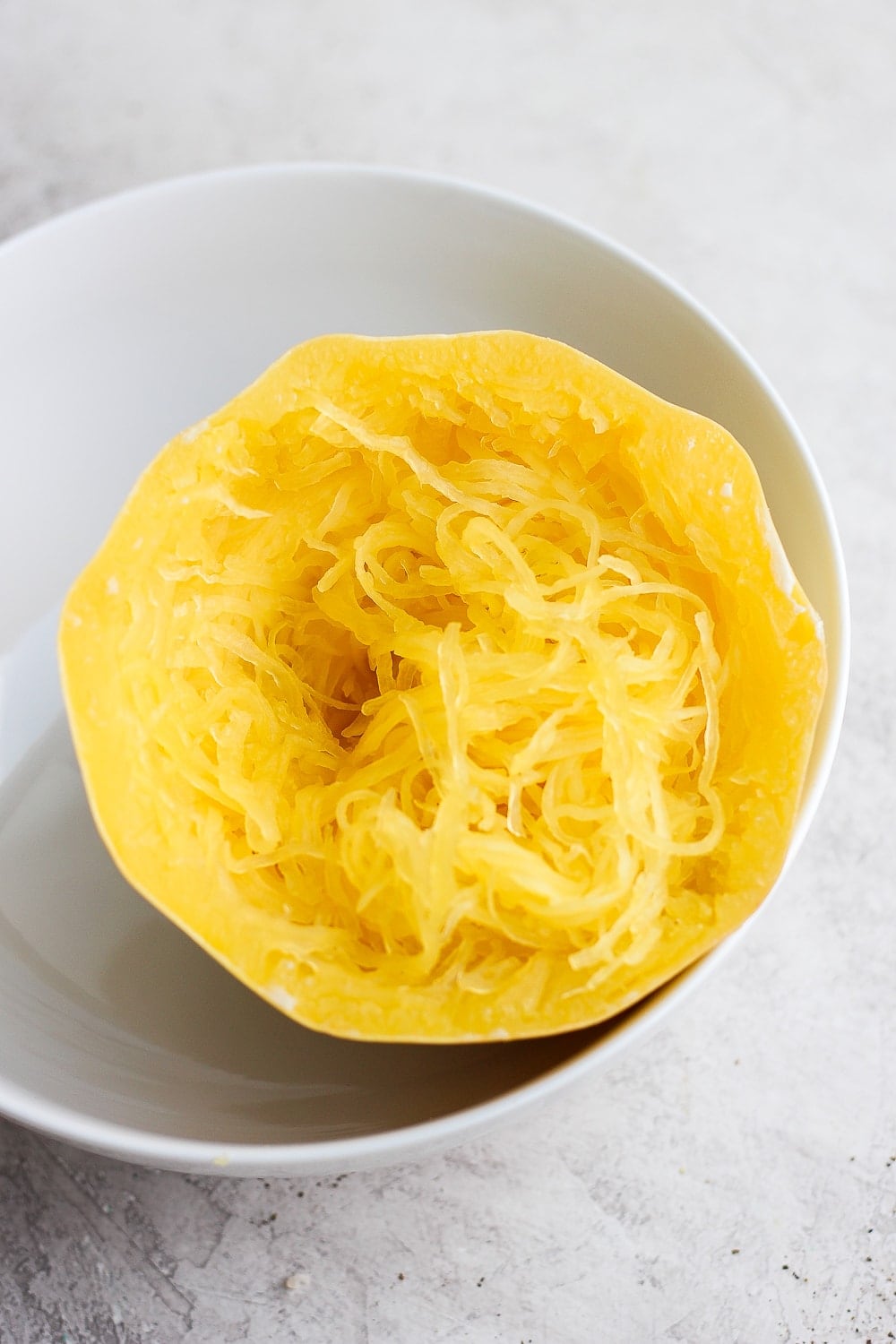 A cooked half of spaghetti squash in a large bowl.