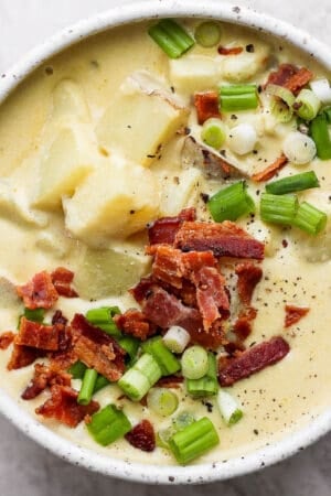 A bowl of loaded baked potato soup with bacon and green onion on top.