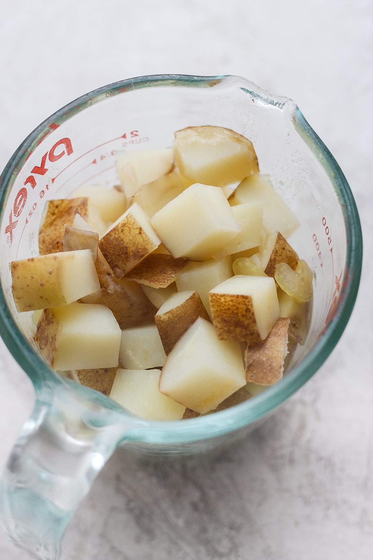 A measuring cup filled with cooked potatoes.