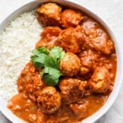 Tikka masala meatballs in a white bowl with cauliflower rice.