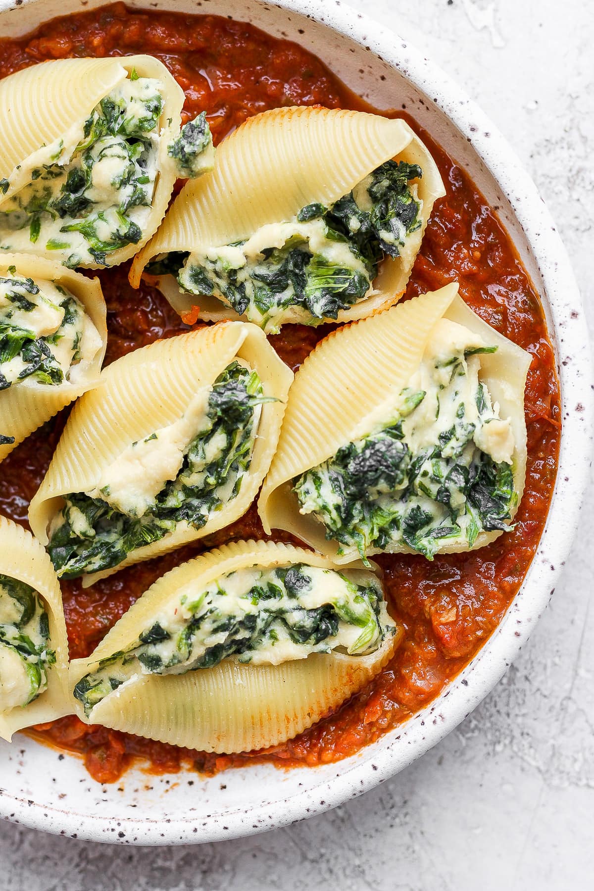 Baked stuffed shells on a plate with the sauce.