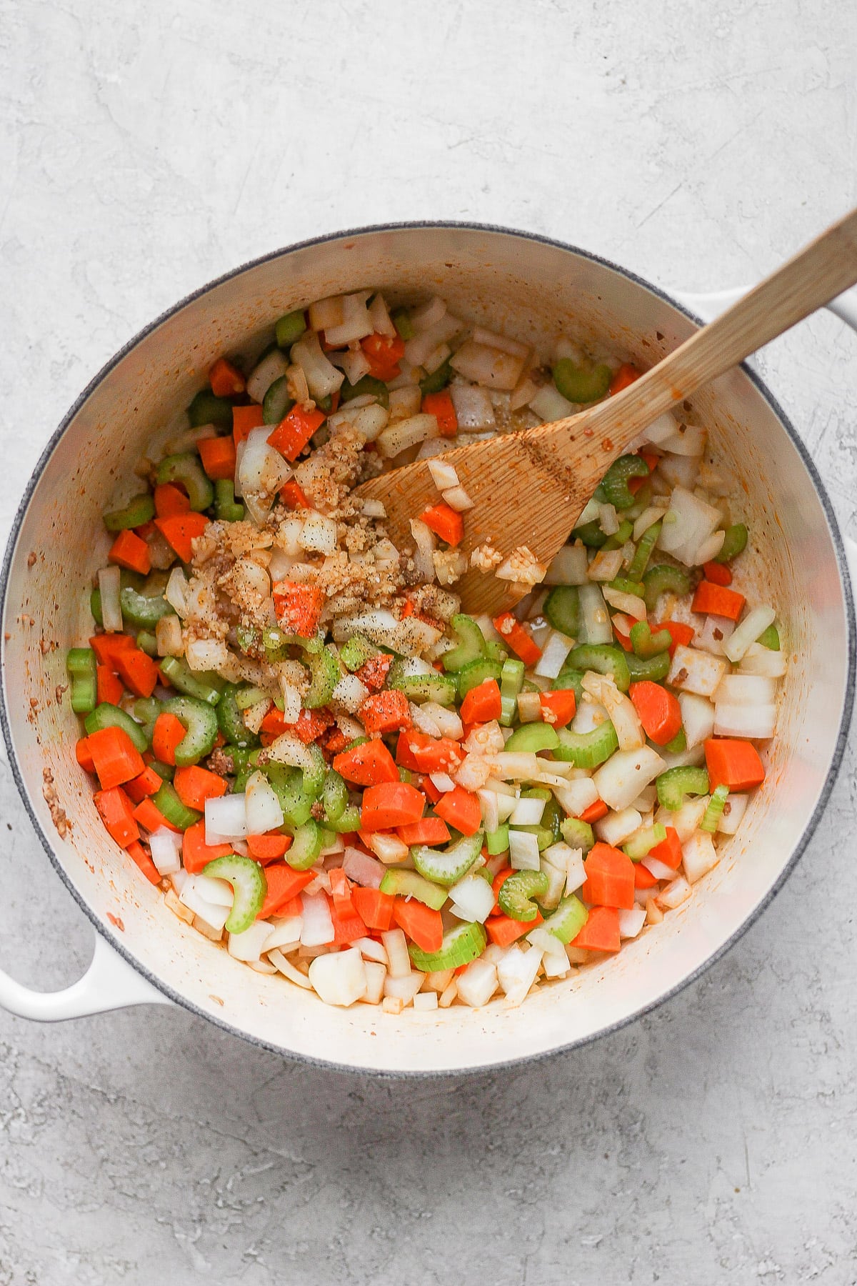 Dutch Oven filled with garlic, onions, celery, carrots and potatoes being sautéed.