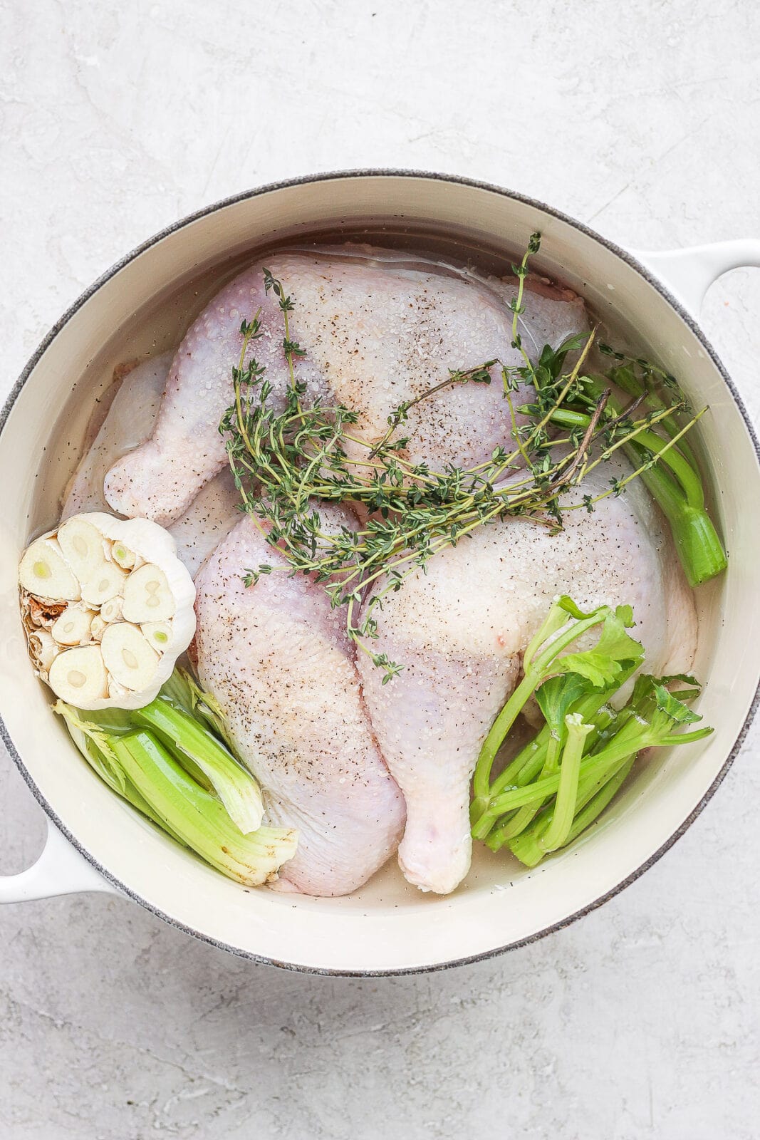 Dutch Oven filled with chicken, water, thyme, celery and garlic. 