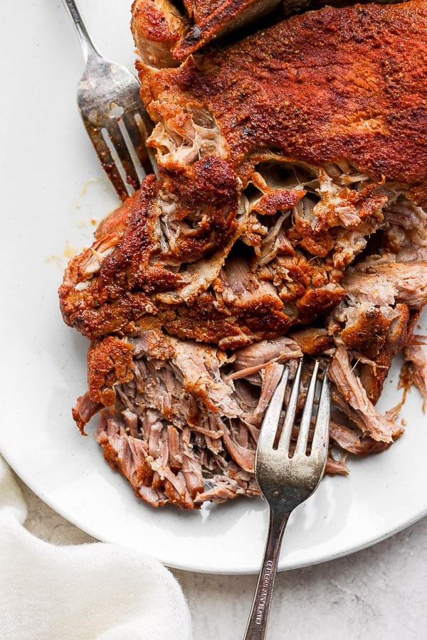 Plate of slow cooked pulled pork and two forks.