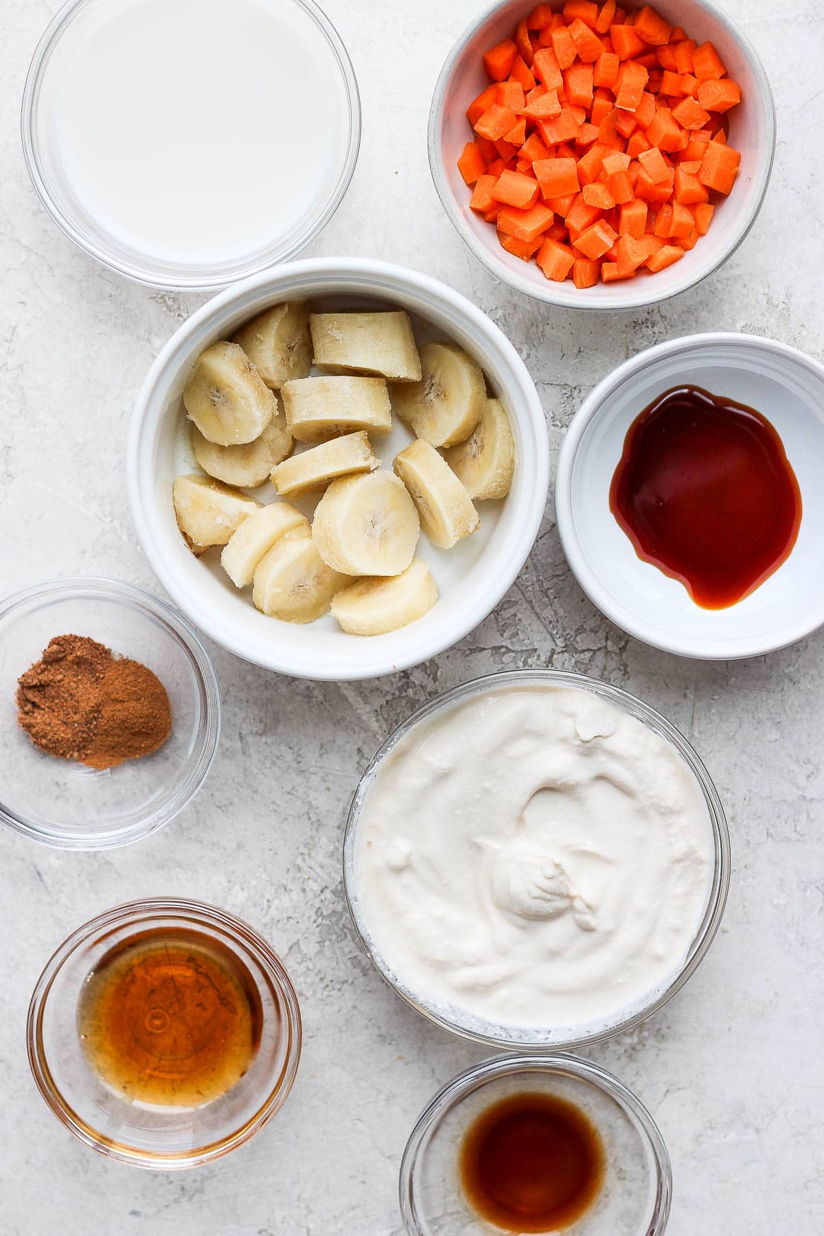 Ingredients for carrot cake smoothie separated in white bowls. 