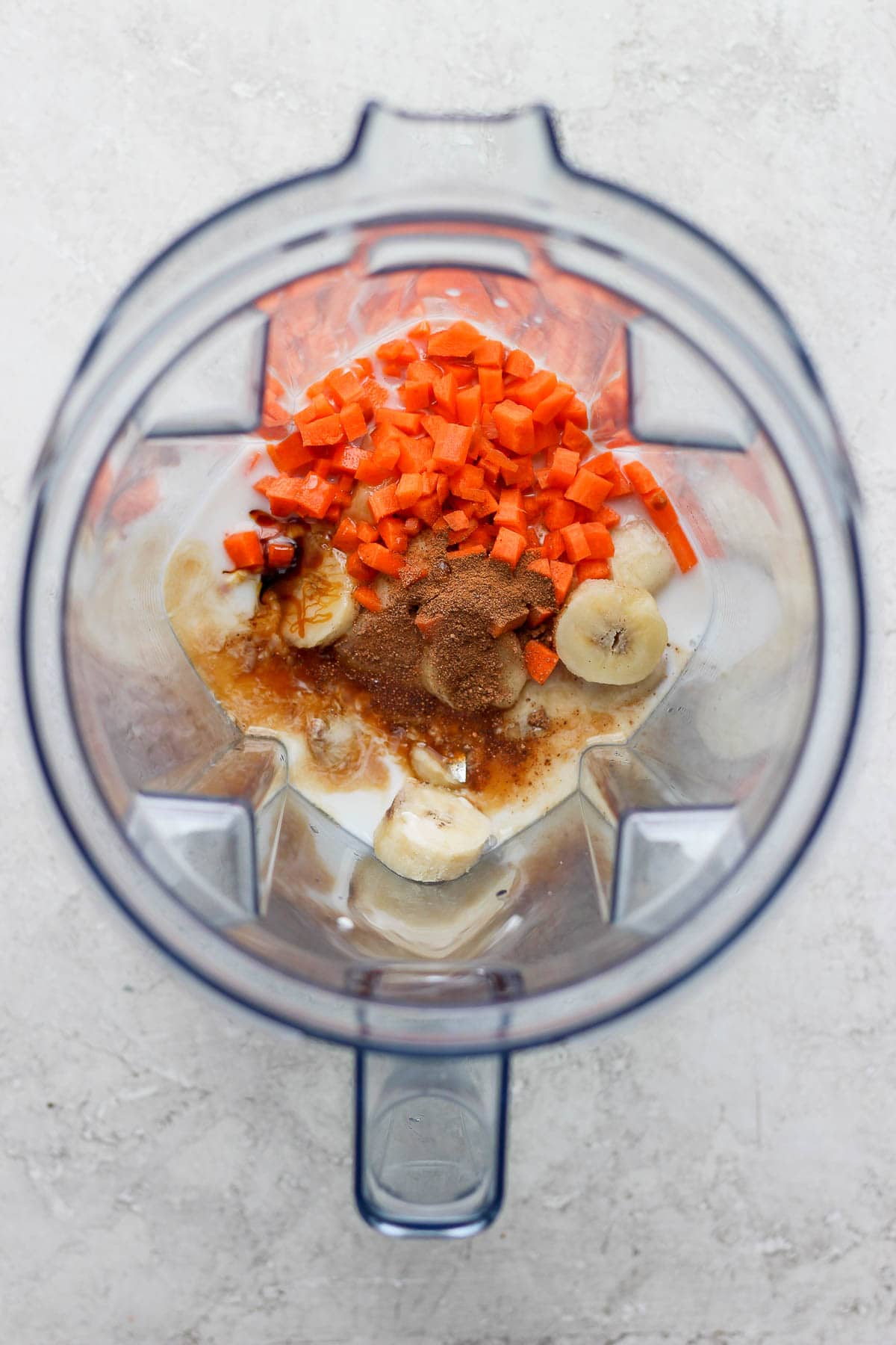 Shot looking into a blender filled with ingredients for carrot cake smoothie. 