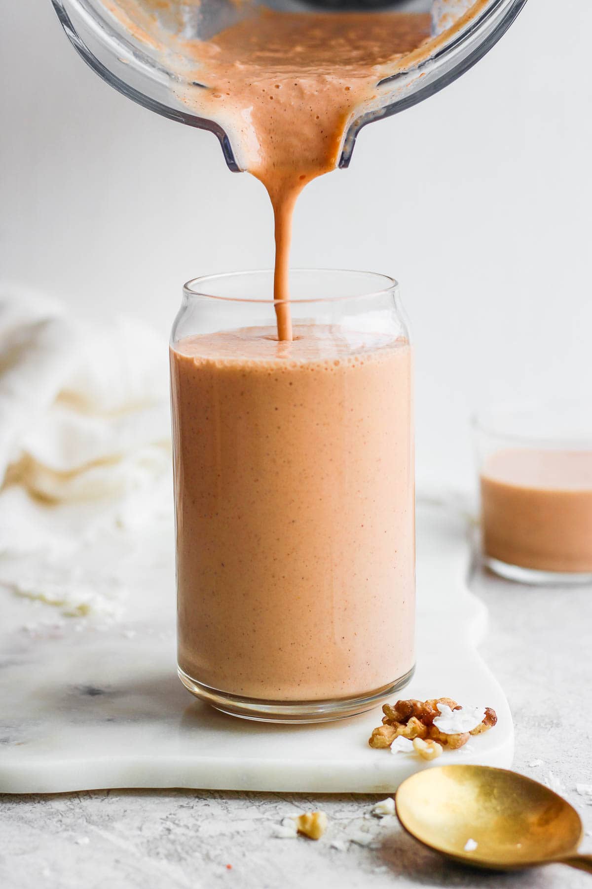 Someone pouring a smoothie into a tall glass. 